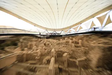Göbeklitepe kazı alanının koruma çatısı altındaki T biçimli dikilitaşları ve taş yapılarının geniş açı görünümü.