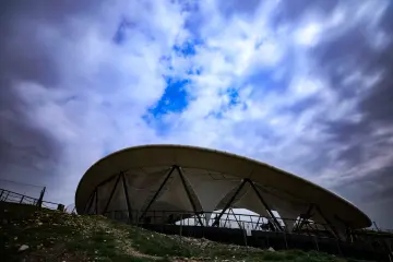 Göbeklitepe koruma çatısının dramatik gökyüzü altında dış cephe görünümü ve modern koruma mimarisi.