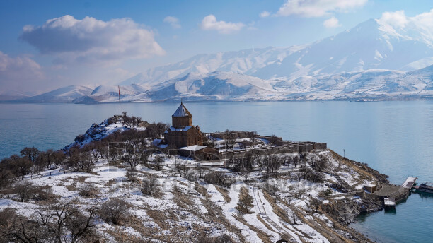 Akdamar Adası ve Akdamar Kilisesi'nin Van Gölü üzerindeki kış manzarasını gösteren panoramik hava fotoğrafı.