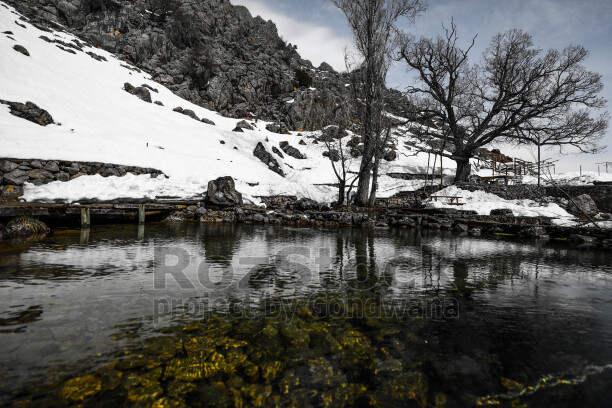 Karlı dağlar, berrak su, doğal göl ve kış manzarası