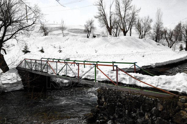 Karlı Munzur Gözeleri, dere üzerindeki küçük köprü ve kış manzarası