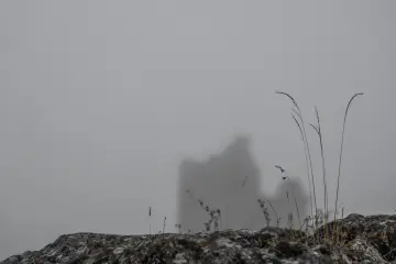 Sisler arasındaki Zerzevan Kalesi silüeti ve Mezopotamya'nın tarihî taş yapısını gösteren atmosferik fotoğraf.
