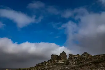 Zerzevan Kalesi taş kalıntıları, bulutlu gökyüzü ve Mezopotamya tarihî mimarisi manzara fotoğrafı.