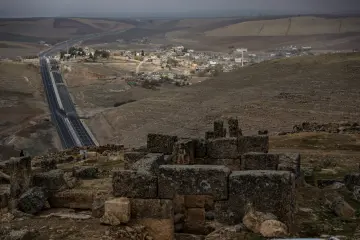 Zerzevan Kalesi taş kalıntıları, Mezopotamya ovası manzarası ve tarihî arkeolojik alan fotoğrafı.