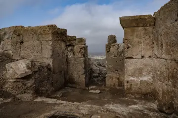 Zerzevan Kalesi'nde taş duvarlar ve tarihi geçidin bulutlu gökyüzü eşliğinde etkileyici görünümü.