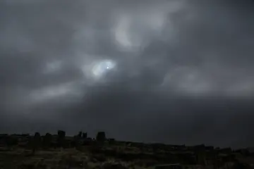 Fırtına bulutları altındaki Zerzevan Kalesi ve güneş ışığıyla oluşan dramatik Mezopotamya manzarası.