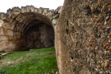 Zerzevan Kalesi'nde kemerli taş yapı ve tarihi duvarlar, Mezopotamya'nın arkeolojik mirasını yansıtan görünüm.